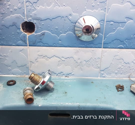 חלקי ברז מפורקים על כיור בחדר אמבטיה